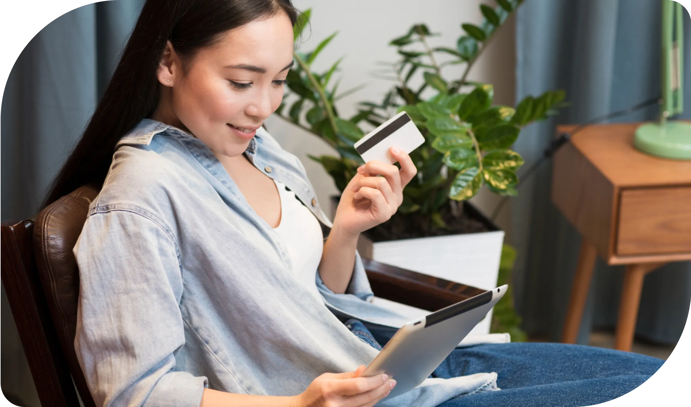 A woman holding a credit card and a tablet.Representing paying off debts